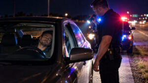 Police officer approaching a sleeping driver in a parked car during a nighttime Texas DWI investigation