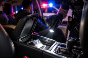 Police officer searching a car where suspected drugs were found in the center console