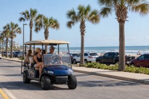 Golf cart carrying passengers on a palm-lined street near the Galveston beachfront